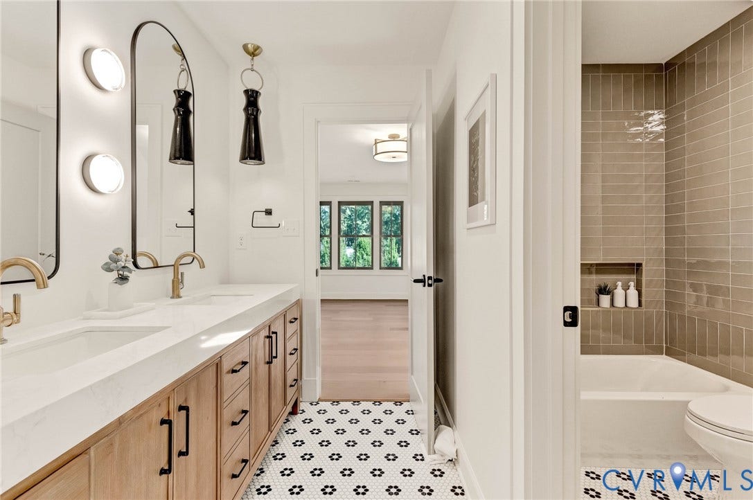 404 Waveny Road, Westham, Henrico, VA 23229 Dual-vanity cabinet with wood-finish cabinetry, quartz countertops, arched mirrors with integrated lighting, matte gold-finish hardware, and geometric patterned floor tiling