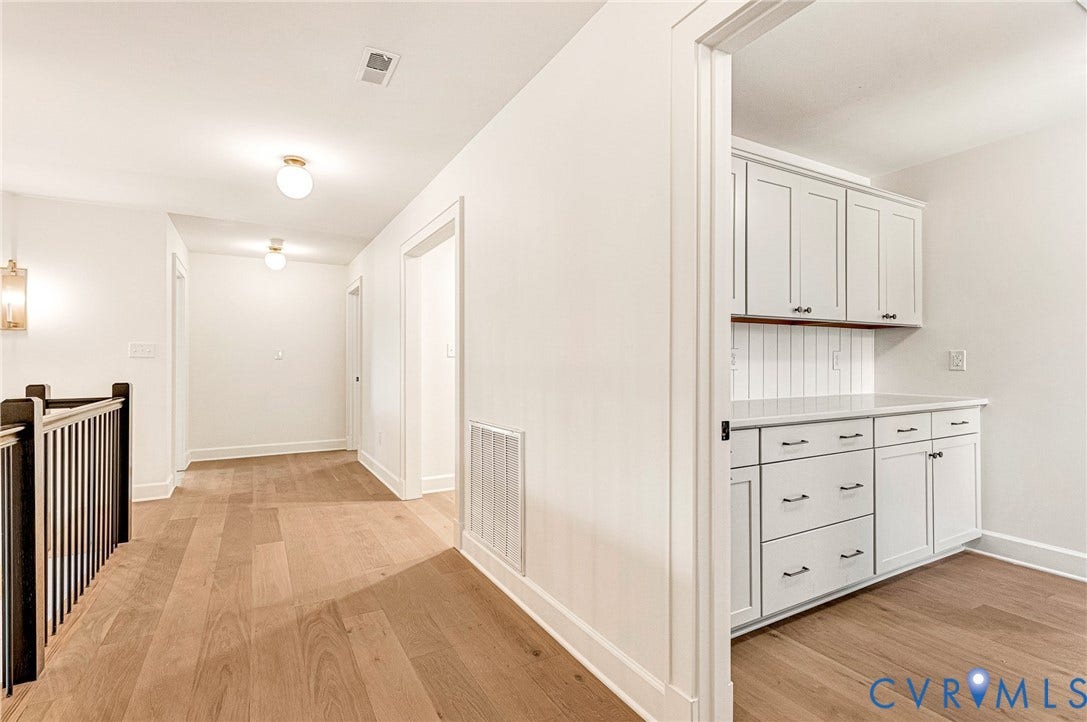 404 Waveny Road, Westham, Henrico, VA 23229 Interior hallway featuring wood-finish flooring, white cabinetry with vertical plank backsplash, and a staircase with a dark-finish railing