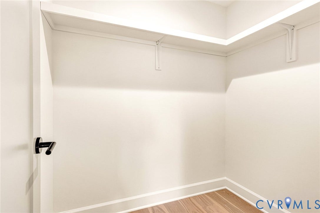 404 Waveny Road, Westham, Henrico, VA 23229 Walk-in closet featuring white wall-mounted shelving with bracket supports, wood-finish flooring, and a matte black lever door handle