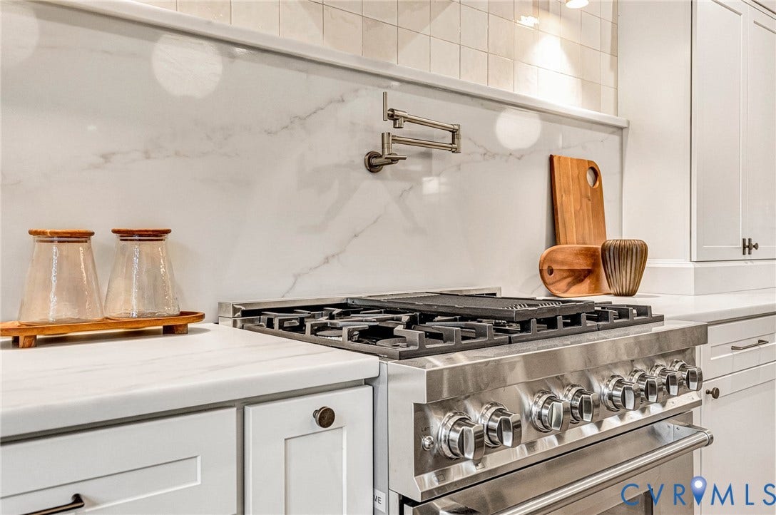 404 Waveny Road, Westham, Henrico, VA 23229 Kitchen featuring a stainless steel gas range with a center griddle, wall-mounted pot filler, solid-surface backsplash, white cabinetry, and light-toned countertops