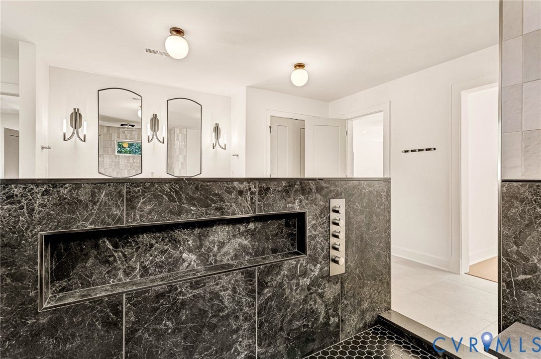 404 Waveny Road, Westham, Henrico, VA 23229 Dark stone shower partition with integrated recessed shelving, multi-head shower control panel, arched wall mirrors, dual globe ceiling fixtures, and matte metallic wall sconces