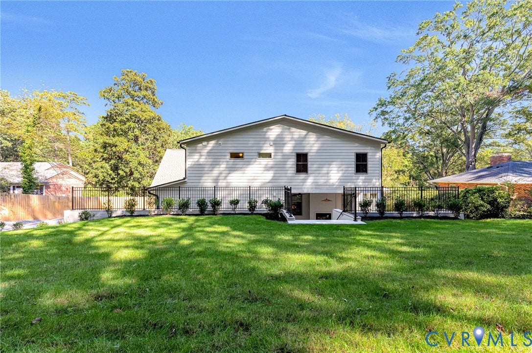 404 Waveny Road, Westham, Henrico, VA 23229 Expansive backyard featuring a manicured lawn, perimeter metal fencing, and established perimeter shrubbery