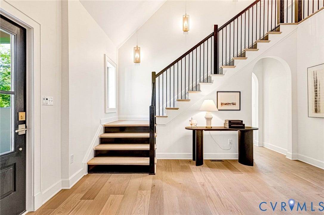 404 Waveny Road, Westham, Henrico, VA 23229 Foyer featuring wood-finish flooring, a vaulted ceiling, a staircase with custom metal railing, and arched architectural details