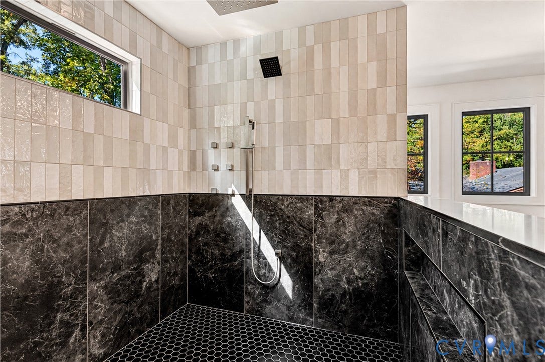 404 Waveny Road, Westham, Henrico, VA 23229 Walk-in shower featuring large-format dark stone wall tiles, cream-toned vertical subway wall tiles, a rainfall showerhead with integrated body jets, and hexagonal floor tiling