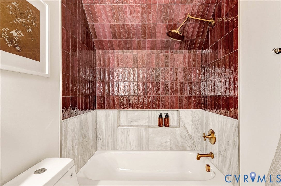 404 Waveny Road, Westham, Henrico, VA 23229 Tub and shower alcove featuring floor-to-ceiling gloss-finish burgundy subway tile, white stone-patterned tile wainscoting, a built-in recessed storage niche, and brushed brass-finish plumbing fixtures