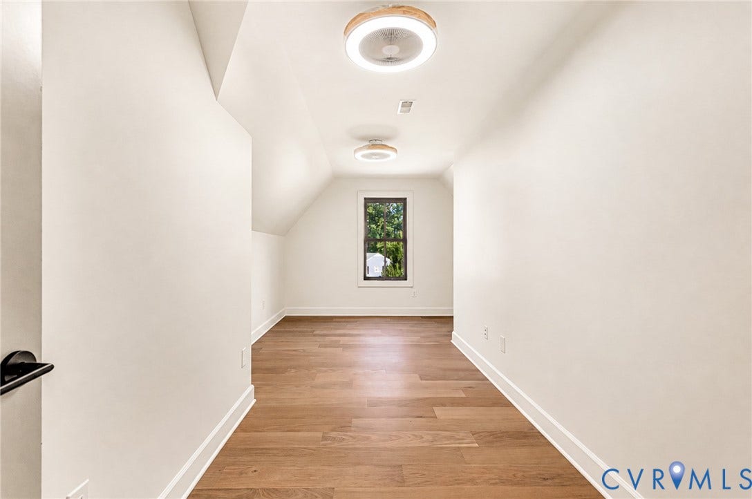 404 Waveny Road, Westham, Henrico, VA 23229 Neutral-toned room featuring wood-finish flooring, sloped ceilings, two circular flush-mount light fixtures, and a single window with dark framing