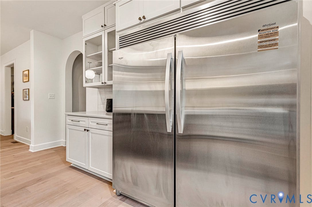 404 Waveny Road, Westham, Henrico, VA 23229 Stainless steel side-by-side refrigerator, white shaker-style cabinetry with glass-front uppers, wood-finish flooring, and an arched wall opening