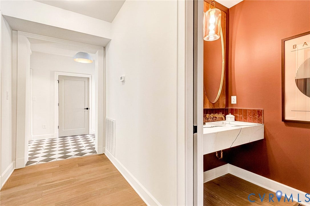404 Waveny Road, Westham, Henrico, VA 23229 Floating vanity with a stone countertop, oval wall-mounted mirror, pendant lighting, and wood-finish flooring