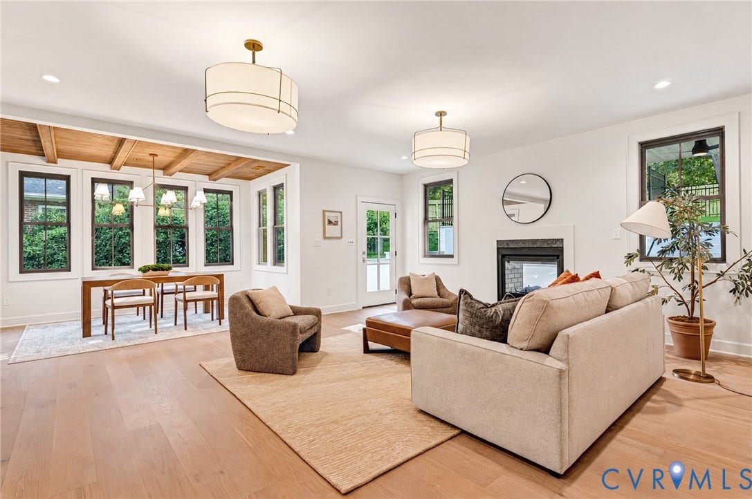 404 Waveny Road, Westham, Henrico, VA 23229 Open-concept interior featuring light wood-finish flooring, exposed wood ceiling beams, a neutral-toned fireplace with a dark surround, and dual drum pendant light fixtures