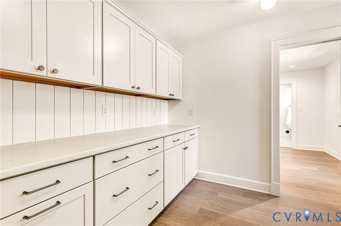 404 Waveny Road, Westham, Henrico, VA 23229 Custom cabinetry with matte finish hardware, quartz countertop, vertical wood-panel backsplash, and wood-finish flooring