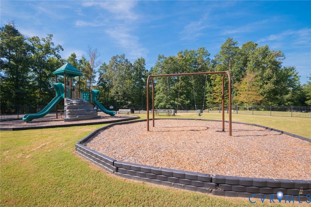 7101 Desert Candle Drive, Moseley, VA 23120 Recreational area featuring a playground structure with slides, a swing set, wood chip surfacing, and a surrounding black metal fence