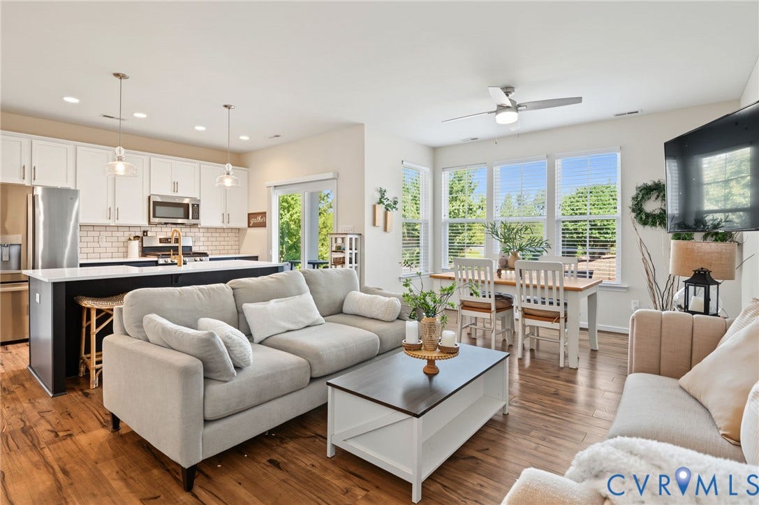 7101 Desert Candle Drive, Moseley, VA 23120 Open-concept living space featuring LVP flooring, a large kitchen island with seating, a full suite of stainless steel appliances, and a dining area with multiple windows