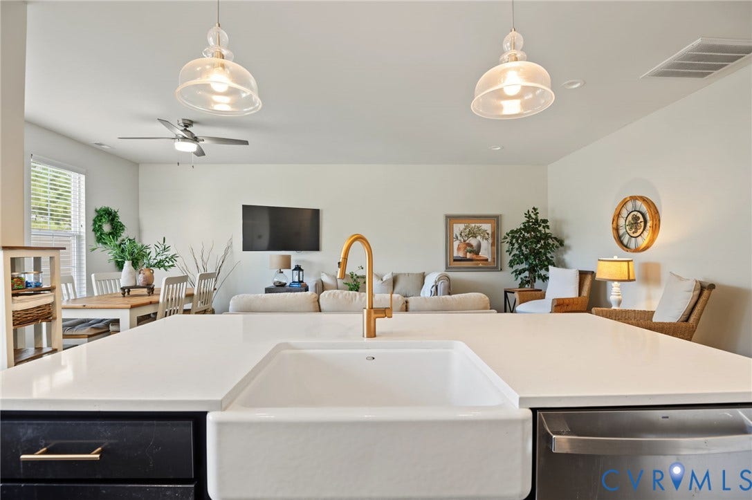 7101 Desert Candle Drive, Moseley, VA 23120 Expansive white island with quartz countertop with an integrated farmhouse sink and a gold-finish faucet