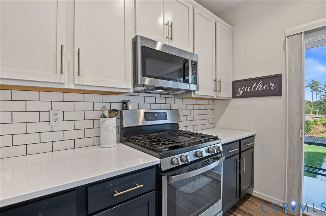 7101 Desert Candle Drive, Moseley, VA 23120 White shaker-style upper cabinetry with brushed nickel hardware, stainless steel microwave, subway tile backsplash, white quartz countertops, and wood-finish flooring