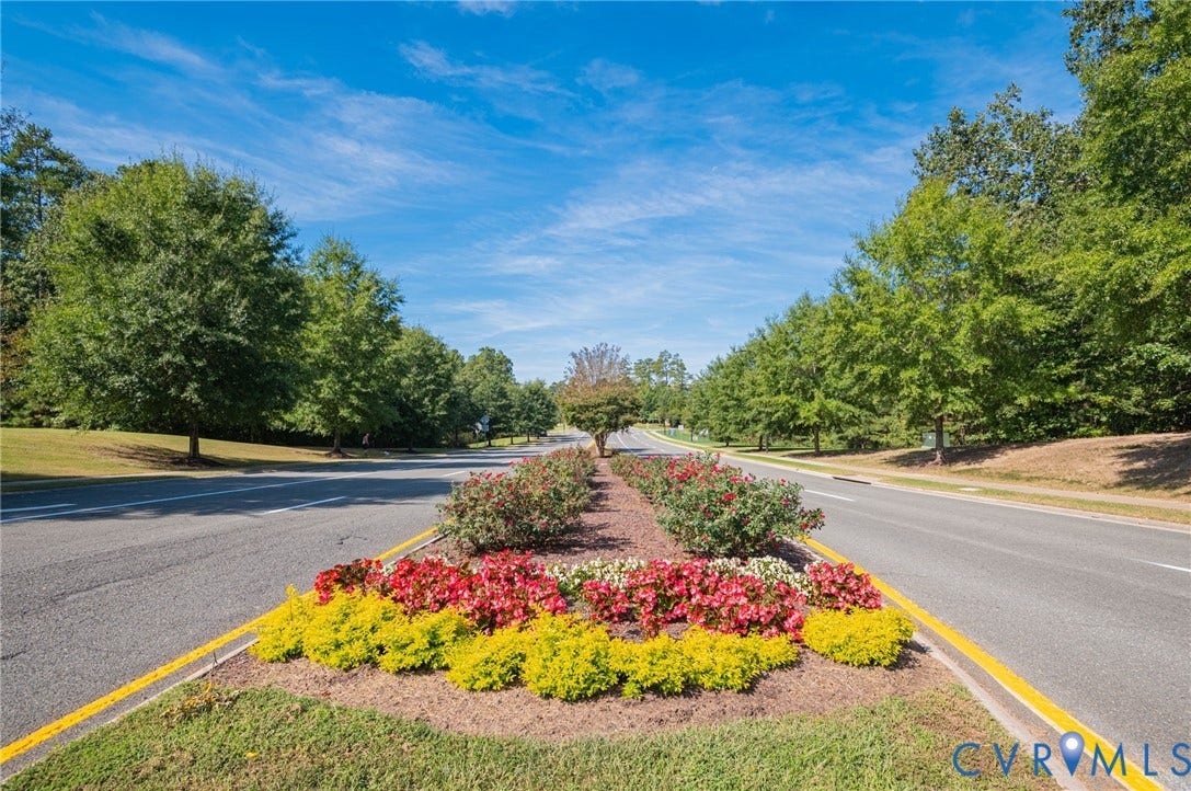 7101 Desert Candle Drive, Moseley, VA 23120 Tree-lined street with a landscaped median featuring colorful planted flowers and shrubs