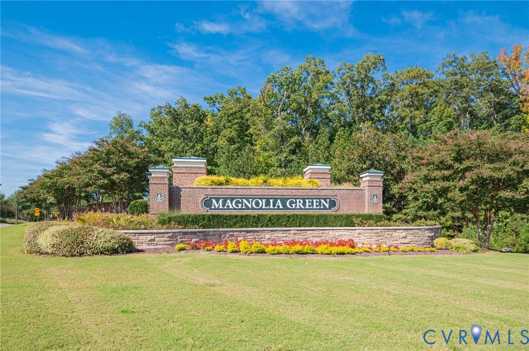 7101 Desert Candle Drive, Moseley, VA 23120 Brick entrance monument with stone veneer accents, lush landscaping, and mature trees