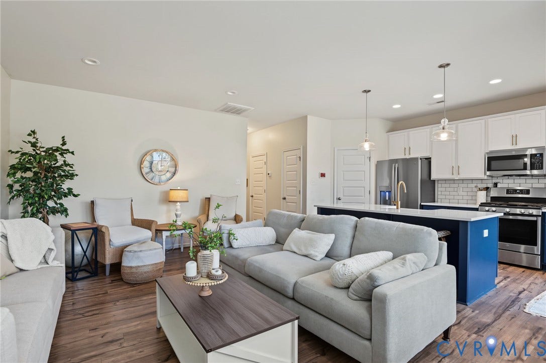 7101 Desert Candle Drive, Moseley, VA 23120 Open-concept living space featuring LVP flooring, recessed lighting, a kitchen island with pendant lighting, white shaker cabinetry, and stainless steel appliances