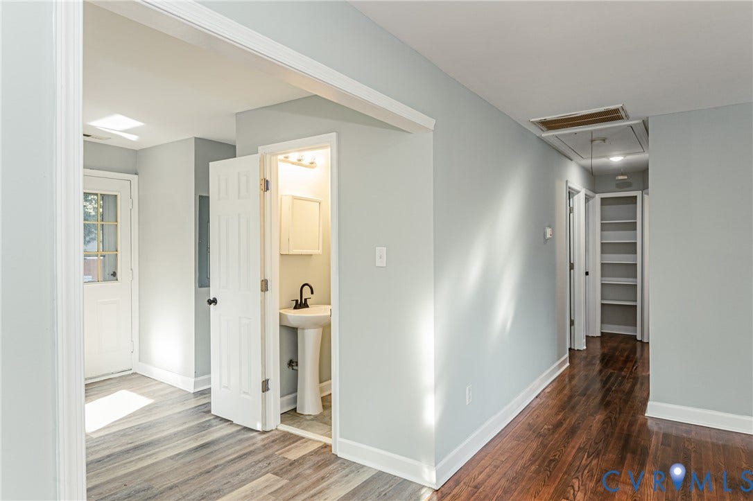 Light gray wall paint, wood-finish flooring, white trim, pedestal sink, and built-in shelving