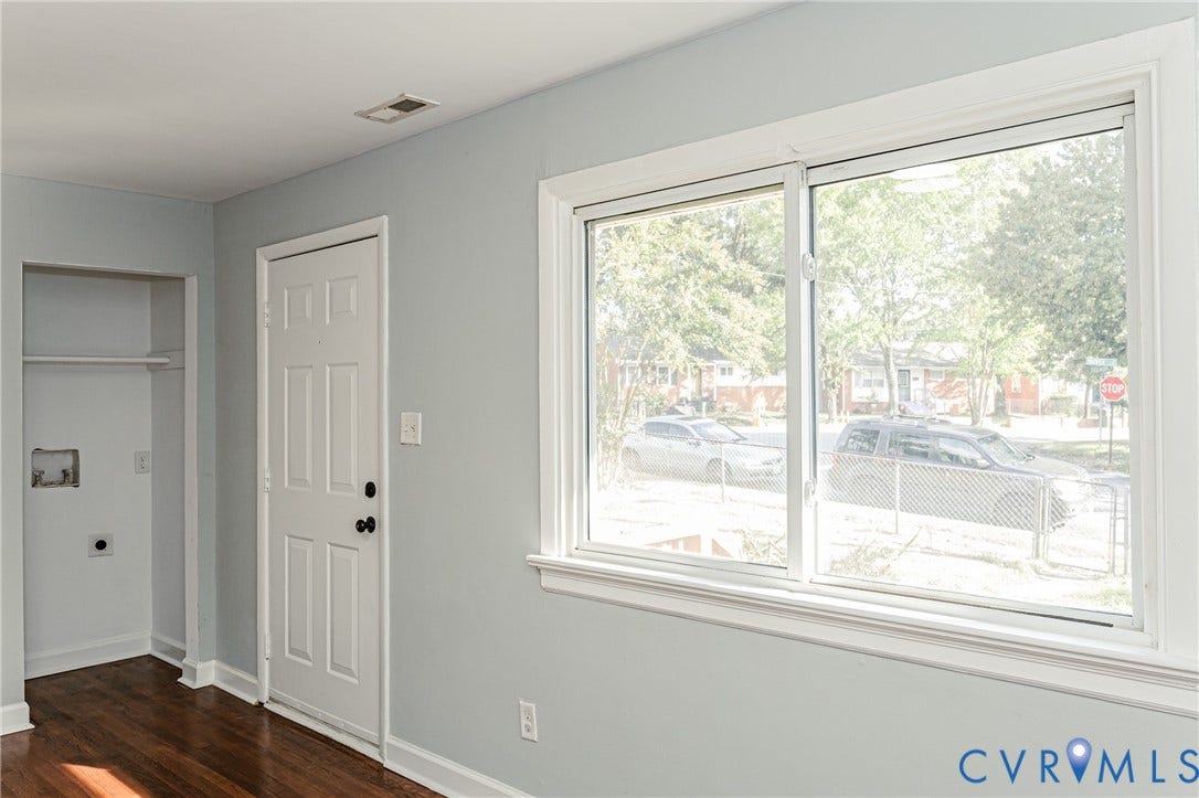 Hardwood flooring, light gray wall paint, white trim, sliding window, and a utility closet with hookups