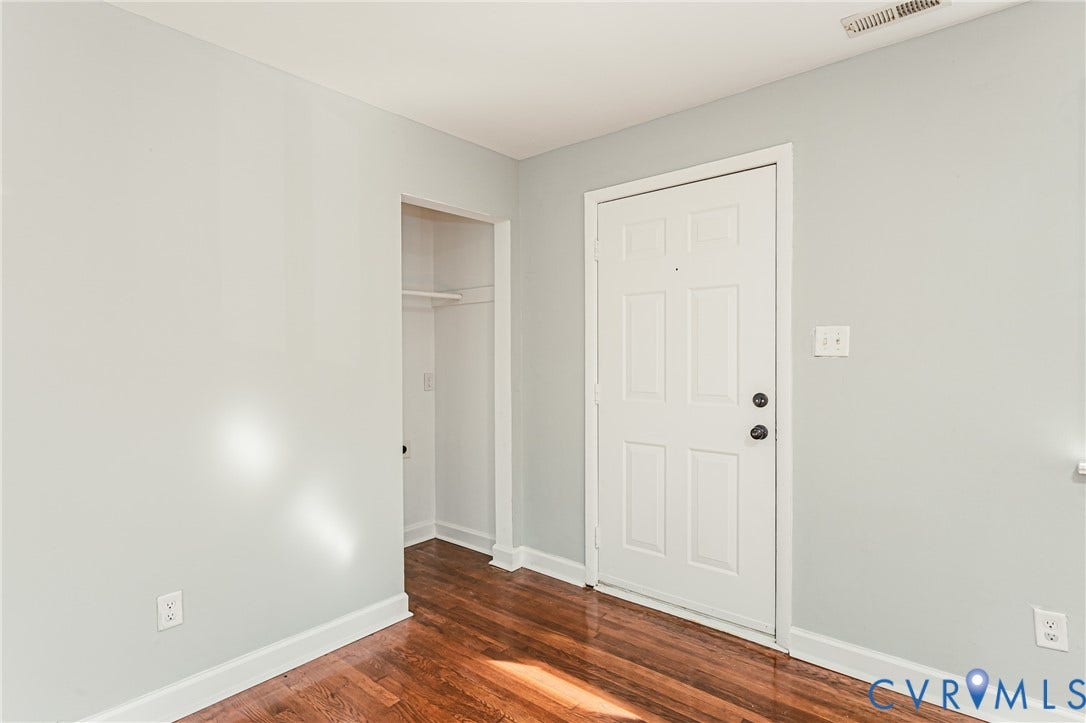 Neutral wall color, wood-finish flooring, white trim, paneled door, and a built-in closet with shelving