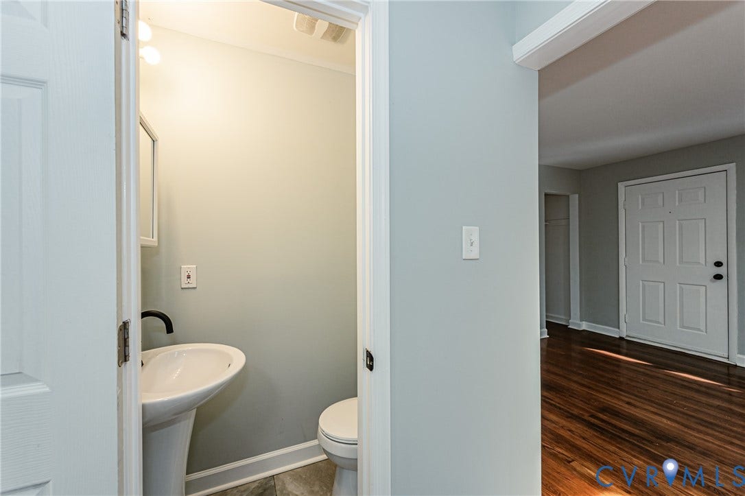 Powder room with pedestal sink, wall-mounted faucet, and tile flooring