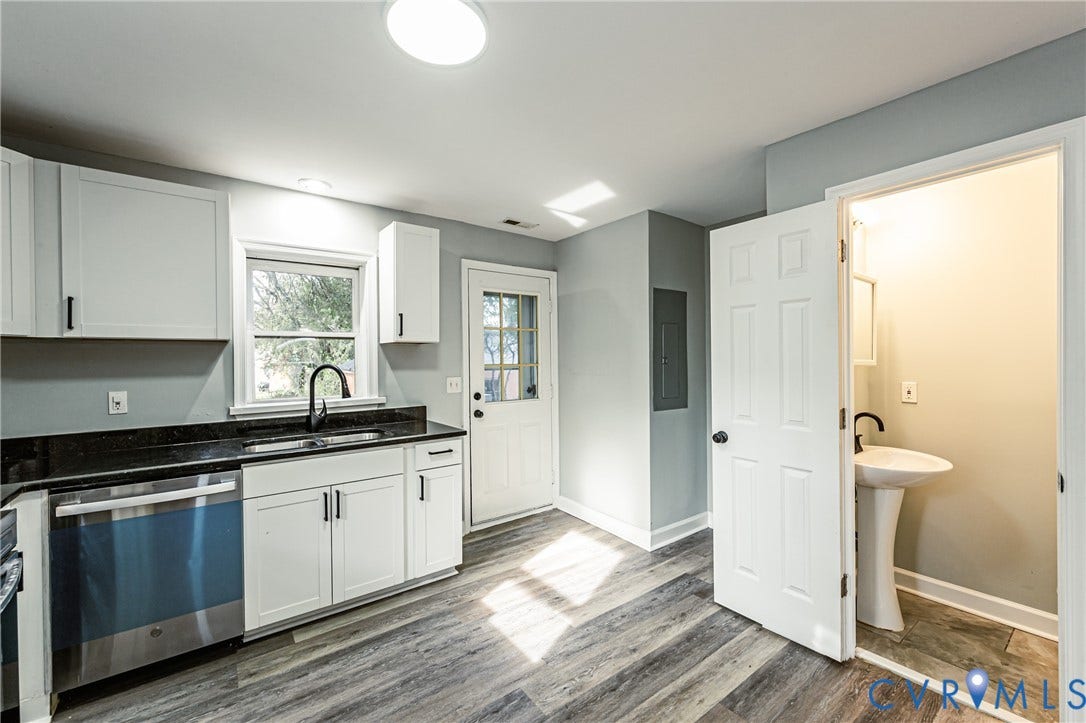 Kitchen featuring white cabinetry, dark countertops, wood-finish flooring, and a stainless steel dishwasher