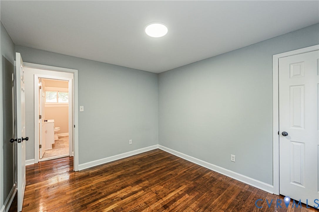 Wood-finish flooring with white trim, light gray walls, and recessed lighting
