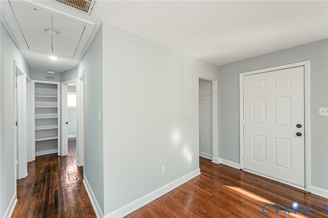 Hardwood-style flooring throughout, light blue wall paint, white trim, recessed lighting, and a white paneled door