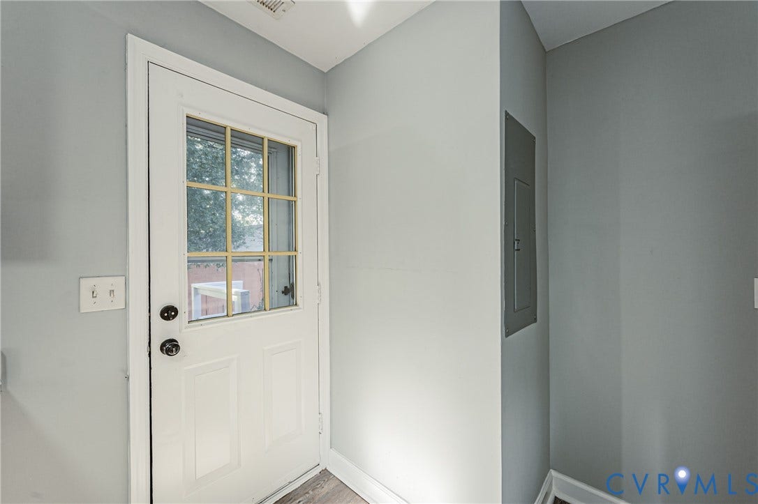 White panel door with nine-light grid, black hardware, and wood-finish flooring