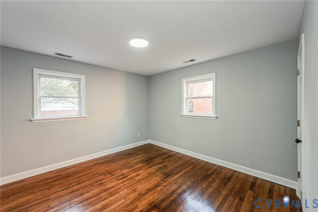 Hardwood flooring, light gray wall finish, two single-hung windows, recessed ceiling light, and white trim