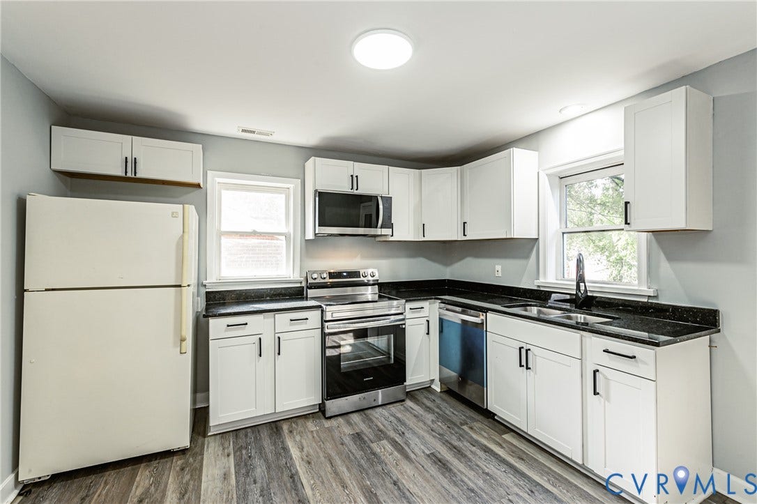 White shaker-style cabinetry with black hardware, dark stone-finish countertops, stainless steel range, and stainless steel dishwasher
