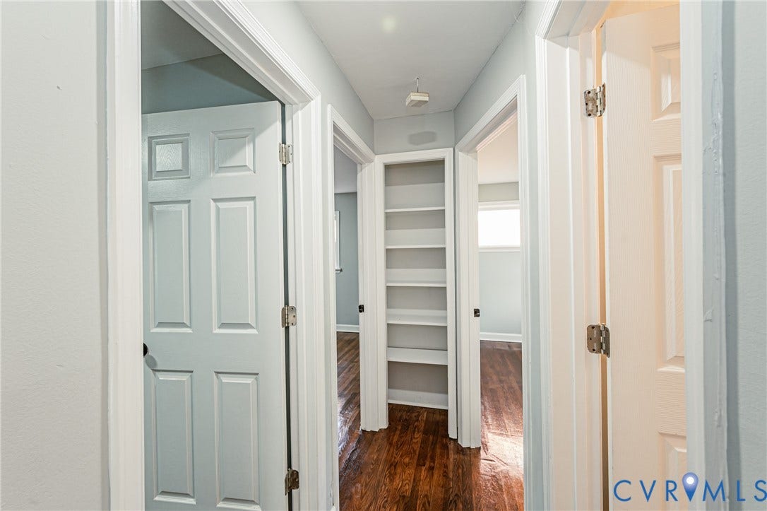 Hallway featuring wood-finish flooring, built-in shelving, and paneled doors