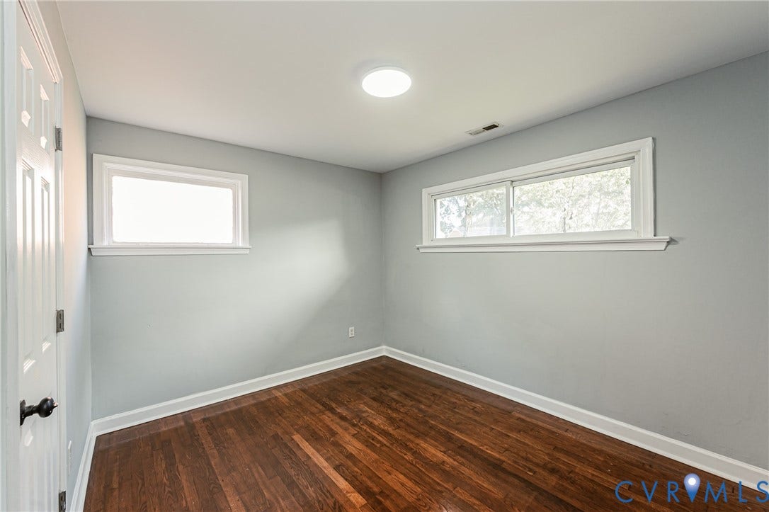Hardwood flooring, painted walls, white trim, recessed lighting, and a white paneled door