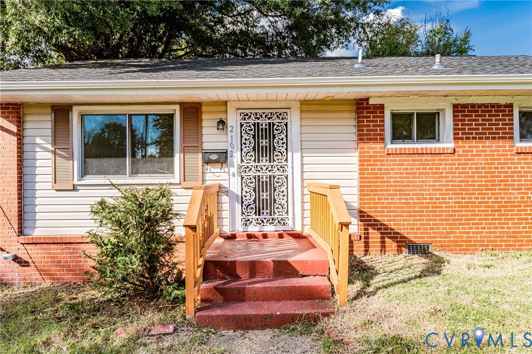Siding exterior with brick accents, wood shutters, and a decorative security door