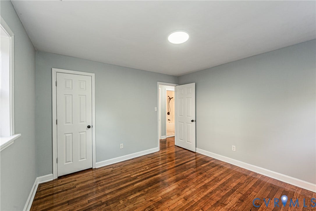 Hardwood flooring with a glossy finish, light gray wall paint, white trim, and a flush-mounted ceiling light fixture