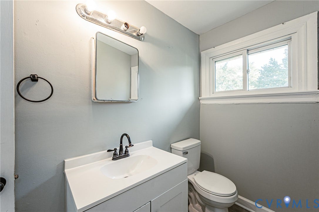 Vanity with integrated sink, black-finish faucet, and a wall-mounted mirror