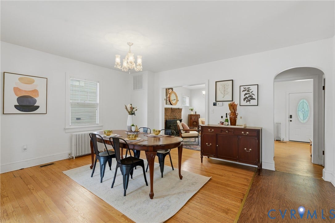 Hardwood flooring, arched doorway, chandelier lighting, and a window with blinds