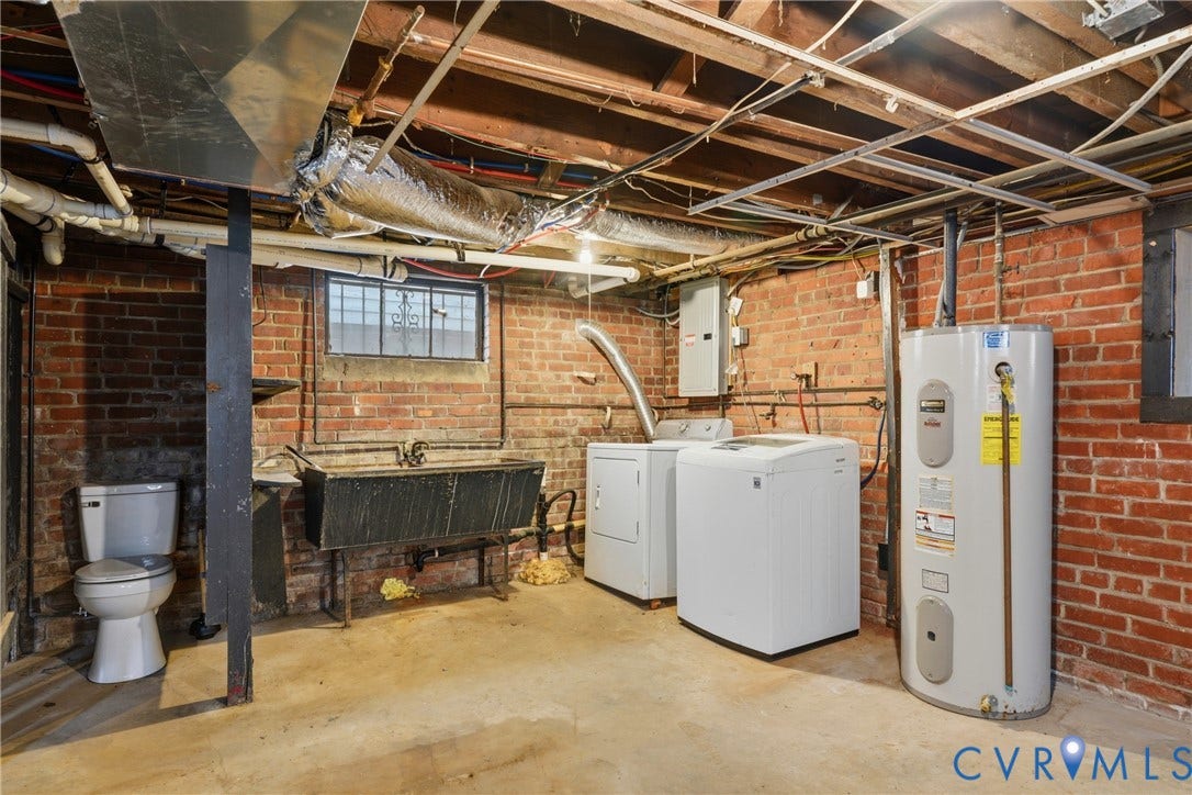 Exposed brick walls, concrete flooring, utility sink, and a water heater