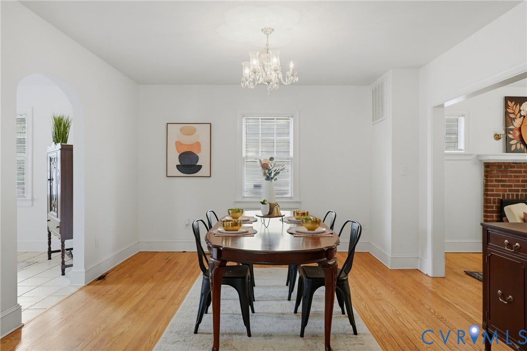Hardwood flooring, arched doorway, recessed window, white walls, and a crystal chandelier