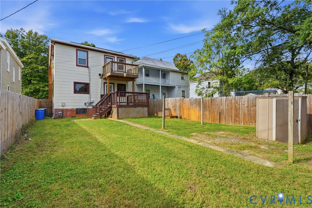 Expansive backyard with a manicured lawn, wood privacy fence, and an exterior storage shed