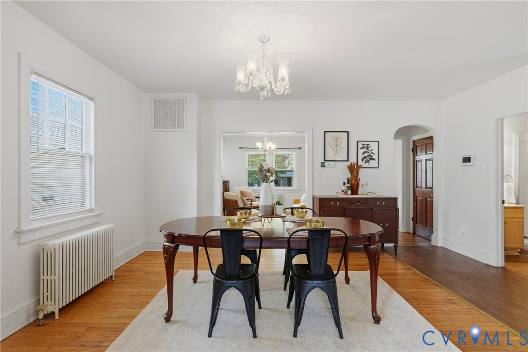 Hardwood flooring throughout, featuring a chandelier, window, and an arched doorway