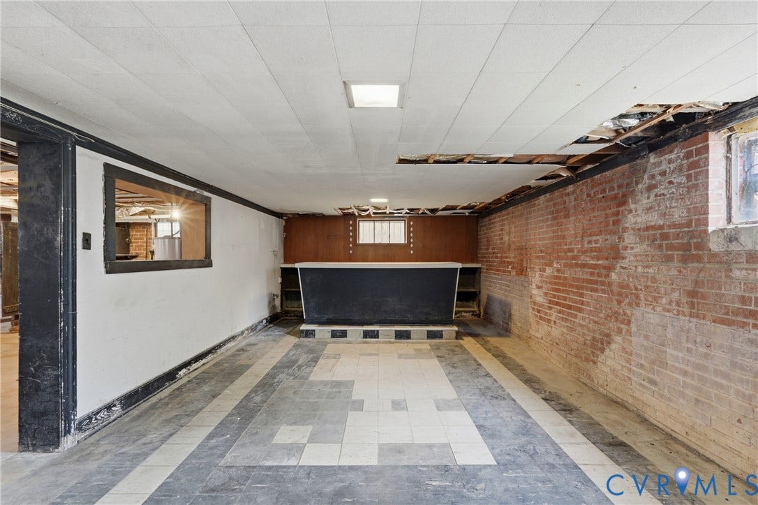 Exposed brick wall, checkered tile flooring, built-in counter space, and a dropped ceiling with integrated lighting