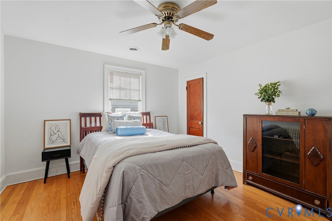 Hardwood flooring, white painted walls, ceiling fan, and a wood-paneled door with white trim