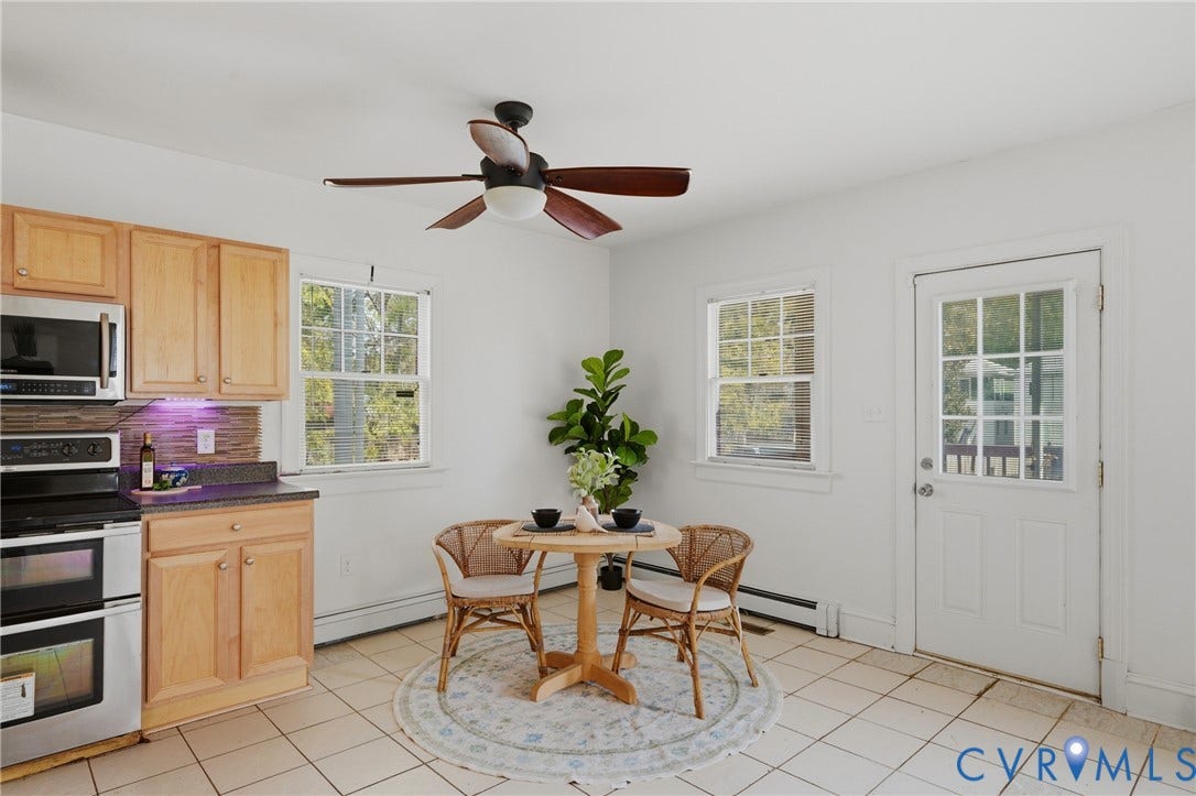 Light wood cabinetry with stainless steel appliances, tiled backsplash, and dark countertops
