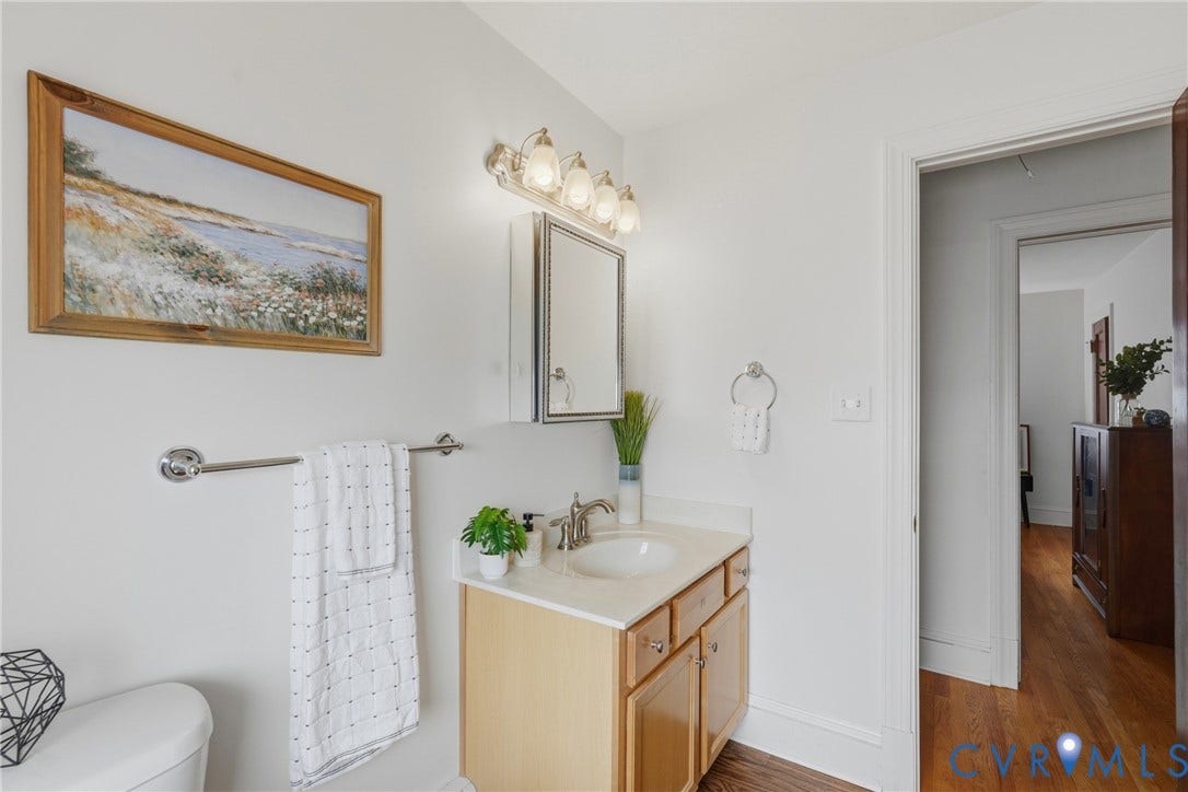Vanity with a neutral countertop, wood-finish cabinetry, and an undermount sink