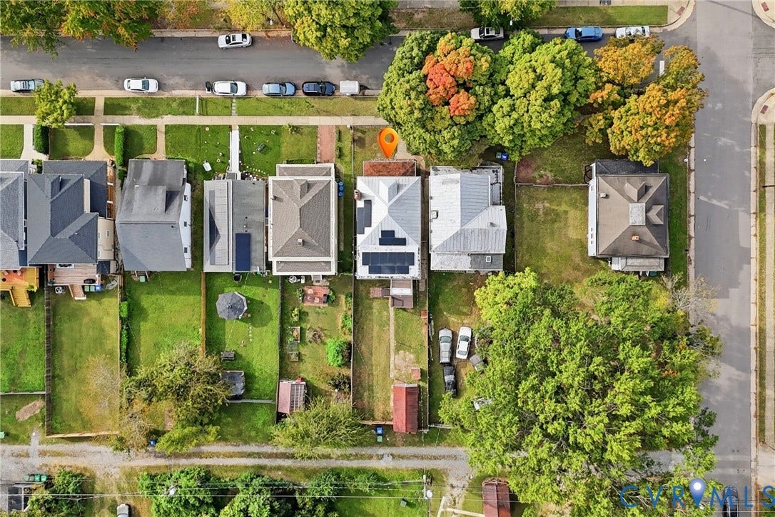 Residential property featuring a rectangular lot, mature perimeter trees, and a paved street