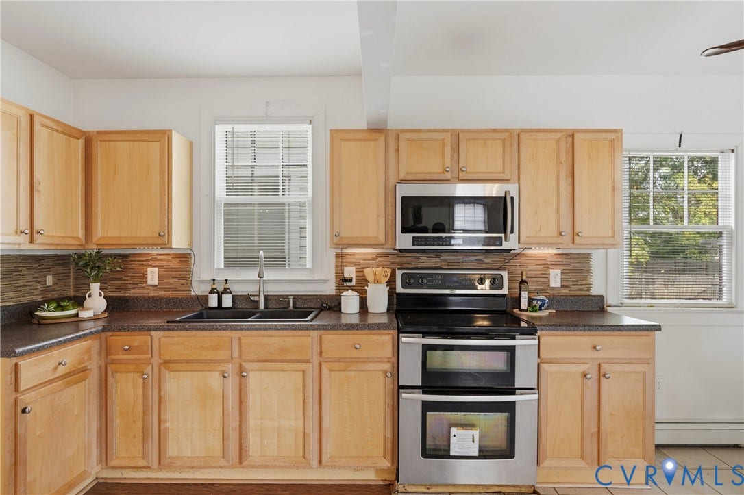 Wood-finish cabinetry, dark countertops, a double basin sink, and stainless steel appliances