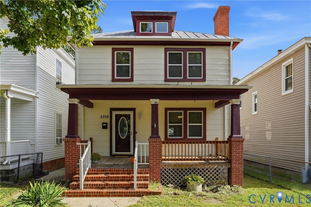 Two-story residence featuring a covered front porch with brick pillars, a dormer window, and a prominent brick chimney