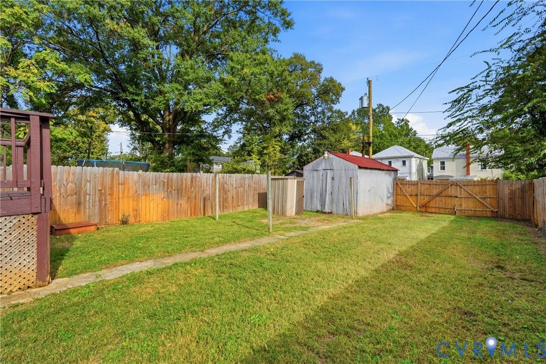 Fenced backyard with a storage shed, wood fence, and a gate