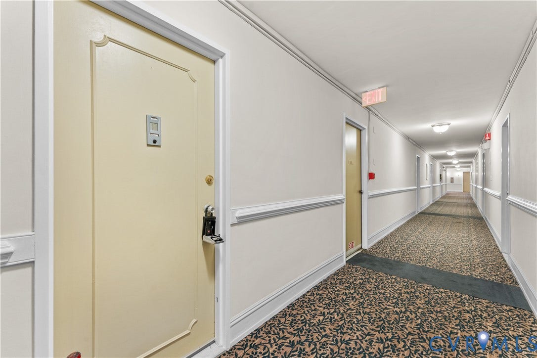 Hallway with patterned carpeting, white walls, and decorative baseboard trim